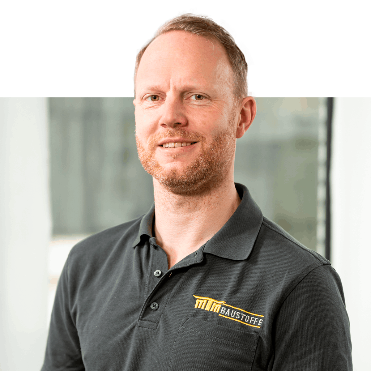 Close-Up Portrait von Markus Kruse, in die Kamera schauend mit schwarzem MTM-Baustoffe Poloshirt