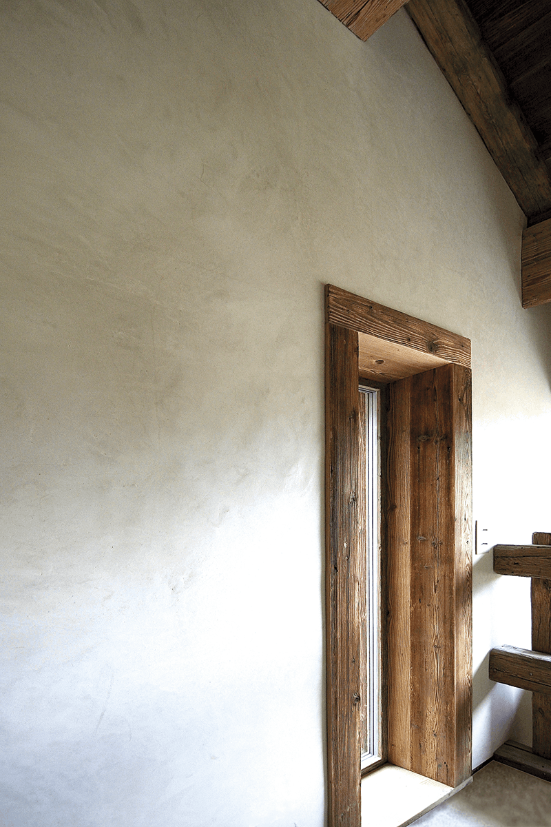 Eine Wand die mit dem Tadelakt STONE hergestellt wurde und in die ein breiter dunkler Holztürrahmen eingesetzt wurde