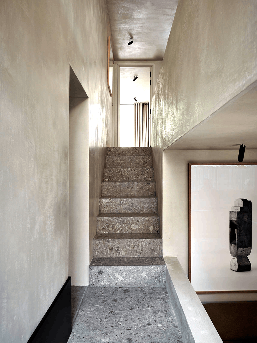 Foto von einem Hausflur mit steingrauer Treppe, in welchem die Wände mit dem Lehmspachtel ANTIQUE PROVENCE in Delphi-Weiß gespachtelt wurden.